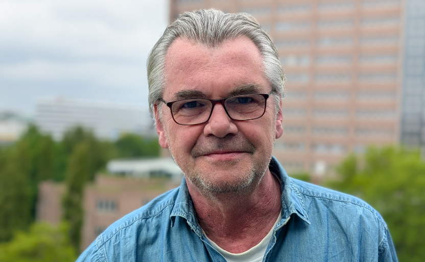 Älterer Herr mit Brille, der ein blaues Hemd trägt.